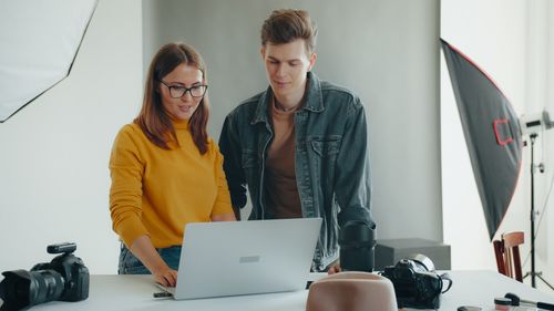 Free Two photographers reviewing images on a laptop in a studio setting. Stock Photo