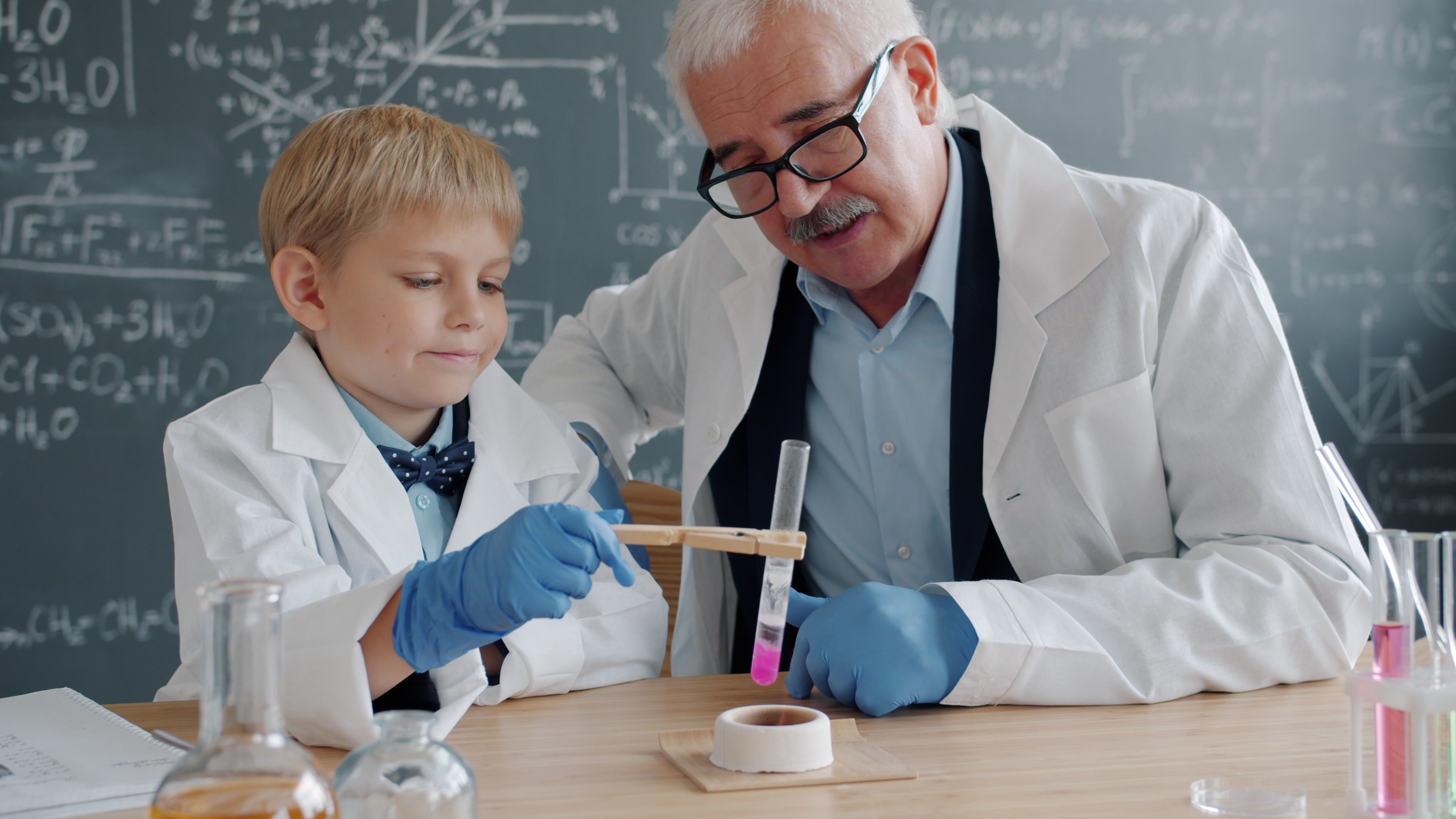 Elderly scientist and young boy conducting a chemistry experiment together.