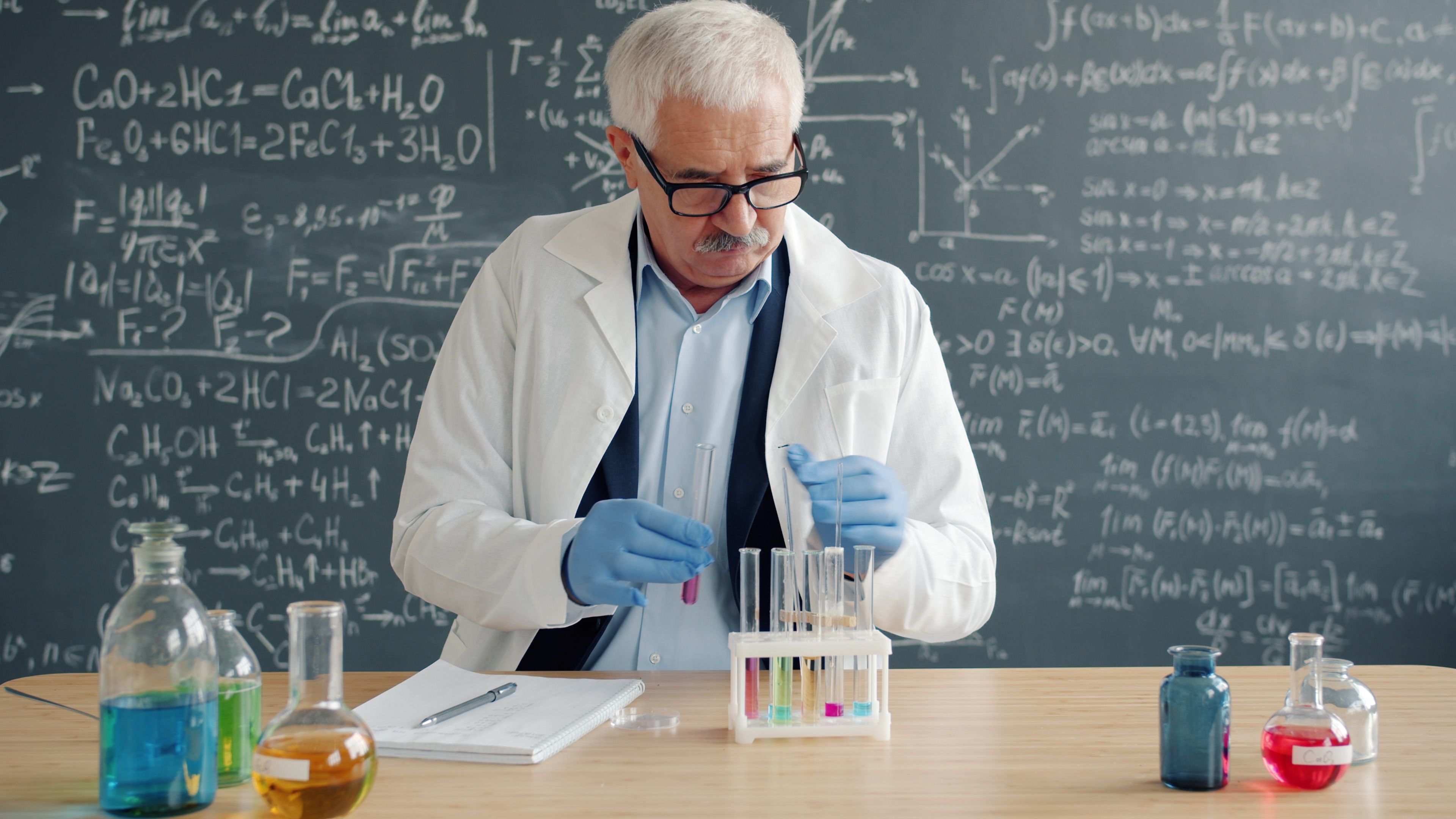 Senior scientist in lab coat designing chemical reactions in a laboratory.