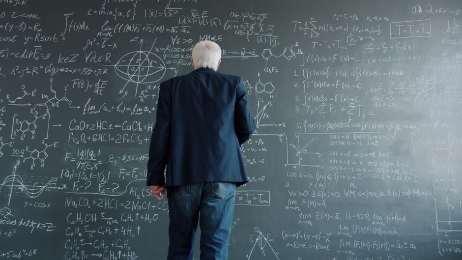 A senior professor in deep thought solving complex equations on a blackboard. A senior professor in deep thought solving complex equations on a blackboard.