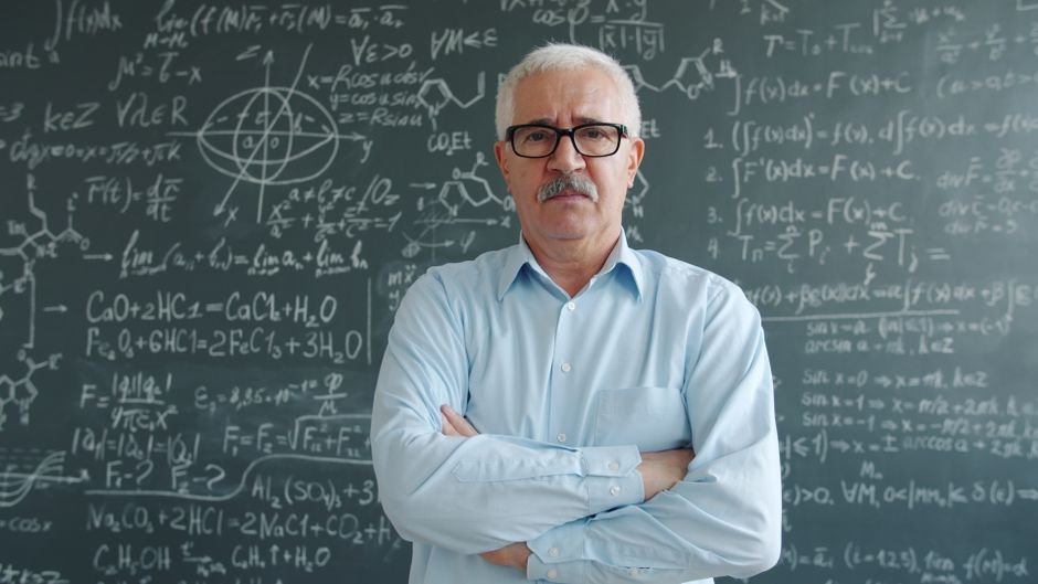 Scientist standing confidently with arms crossed before a chalkboard filled with complex equations. Scientist standing confidently with arms crossed before a chalkboard filled with complex equations.
