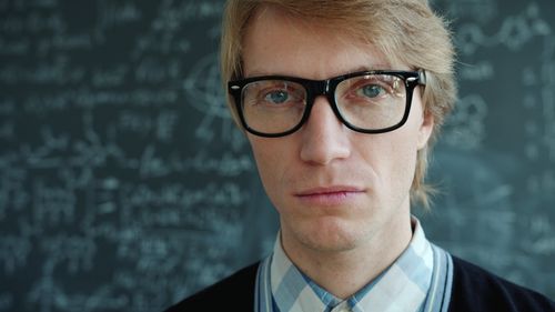 Free Portrait of an academic professional in front of a chalkboard with math formulas. Stock Photo