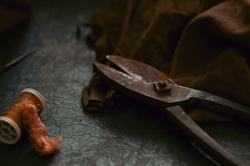 Free A close-up of vintage scissors, thread, and brown fabric in a moody, artistic composition. Stock Photo