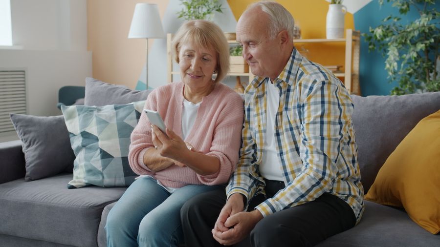 Husband and wife at home on the phone with Senior Peace Care, relieved and smiling