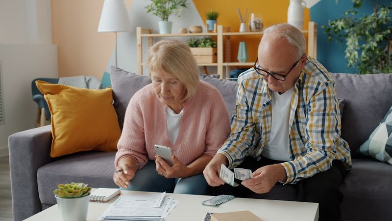 An elderly couple budgeting together at home, symbolizing end-of-life financial preparation