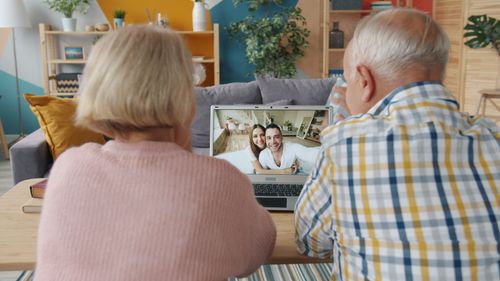 Free Senior couple enjoying a video call with family members on a laptop in a cozy living room. Stock Photo
