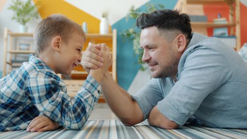 Free Father and son bonding through a playful arm wrestling match at home. Stock Photo