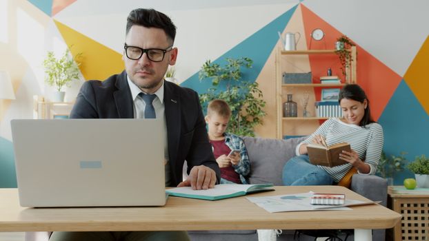 Family working and relaxing in a modern home office space with a laptop and books.