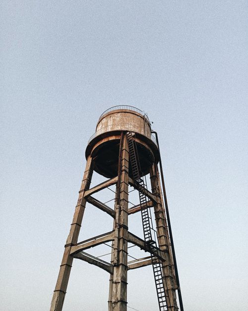 Free Aged water tower with rust and metal structure against a clear sky. Stock Photo