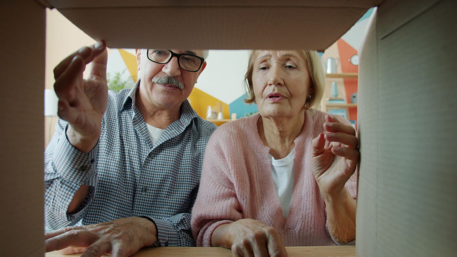 An older couple leaning in to look inside an open cardboard moving box