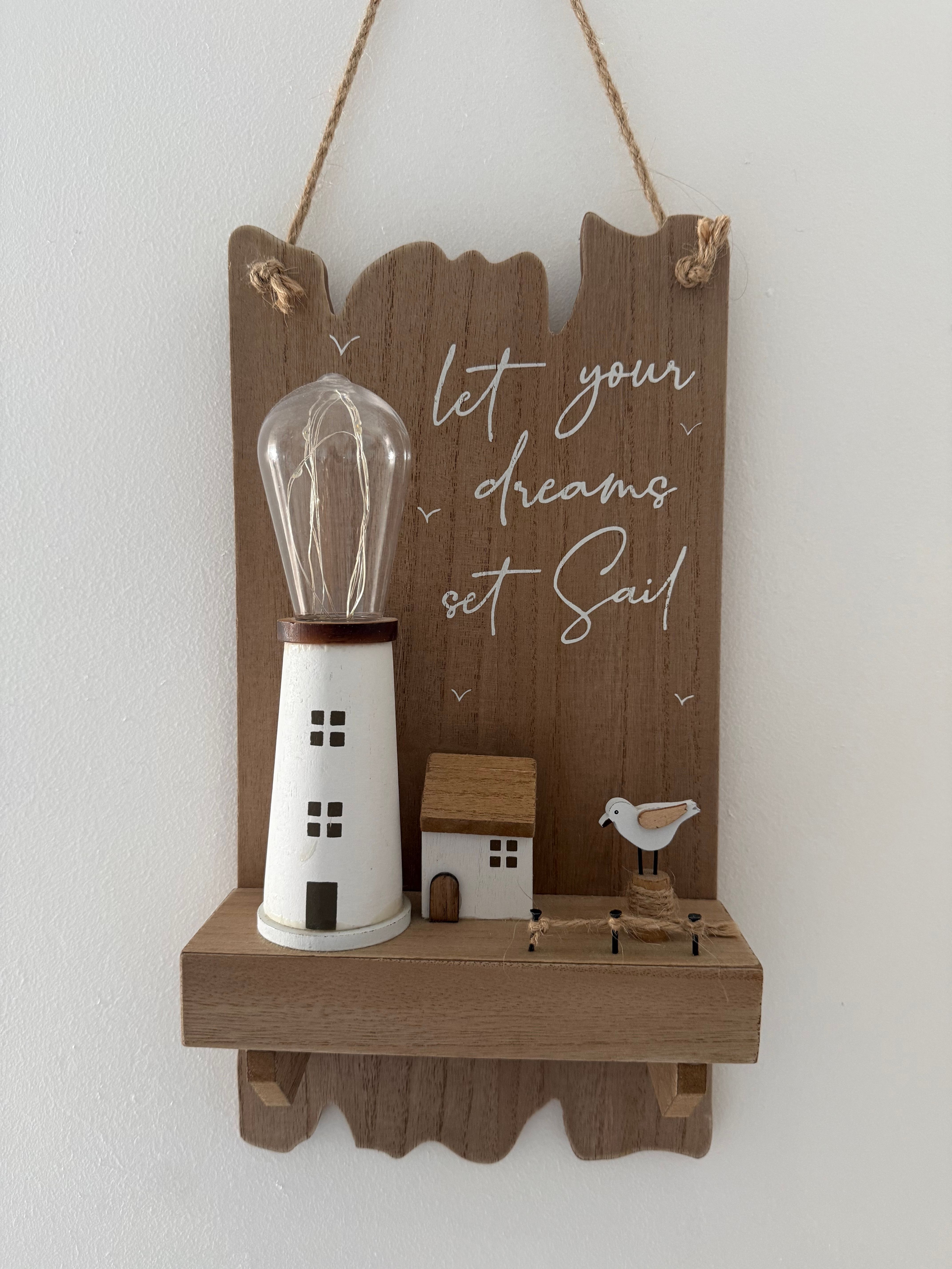 Wooden wall decor with lighthouse and inspiring quote for coastal home style.
