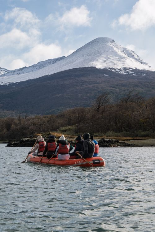 Free Adventurers canoeing in Lapataia Bay with stunning snow-capped mountains in the background. Stock Photo
