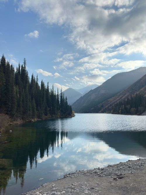 Free Beautiful mountain lake with pine trees and mountain reflections in Kazakhstan under a blue sky. Stock Photo