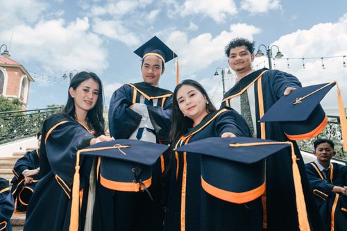 Free A group of young adults celebrating their graduation with caps and gowns outdoors. Stock Photo