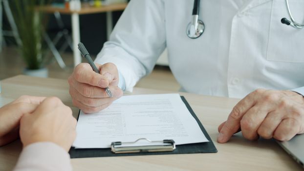 Close-up of doctor and patient reviewing medical documents during consultation.