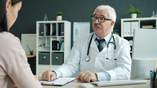 Médico conversa com paciente durante consulta de rotina em consultório