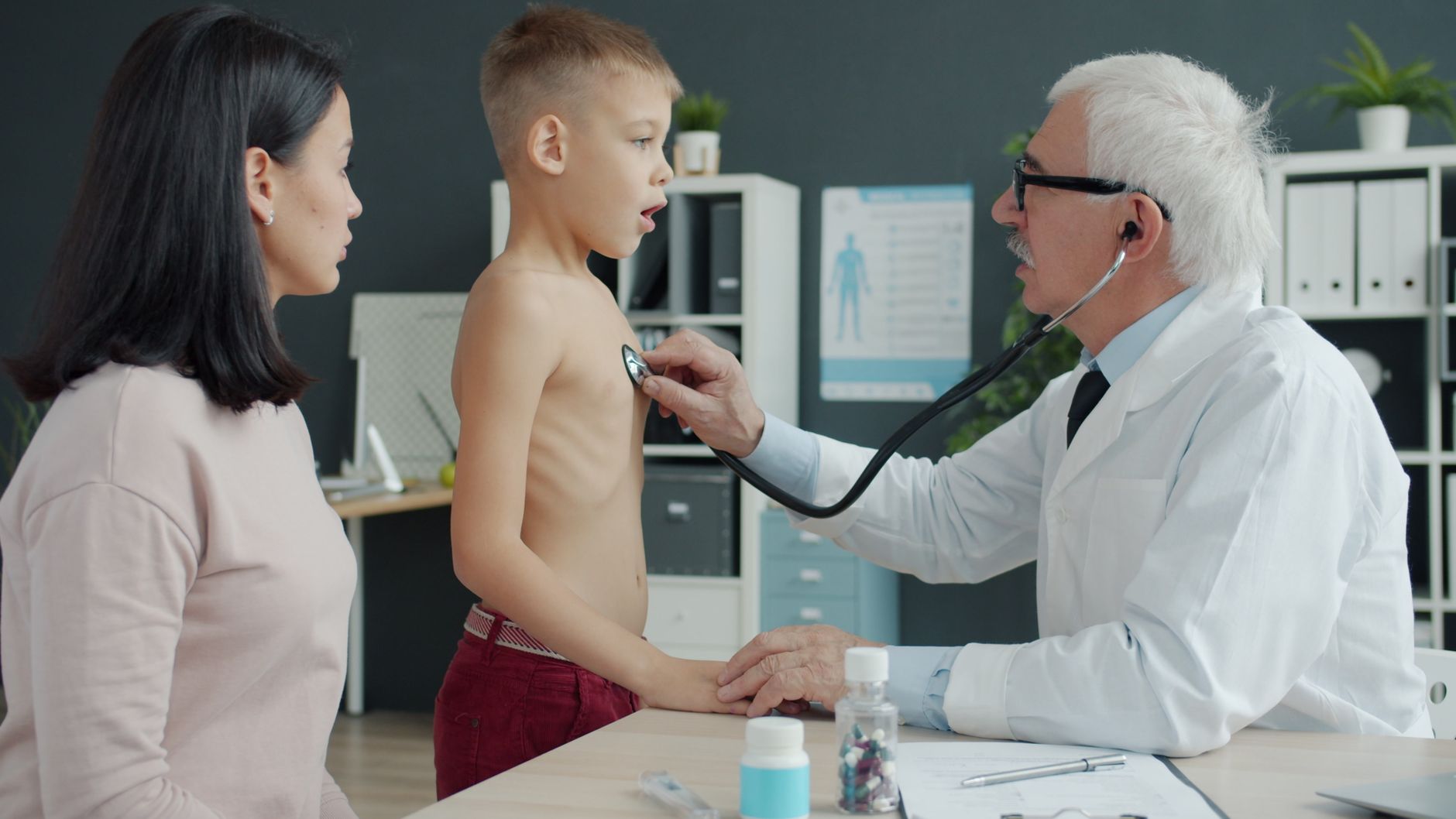 A doctor uses a stethoscope to examine a child in a clinical setting.