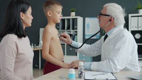 Free A doctor uses a stethoscope to examine a young boy with his mother present in a medical office. Stock Photo