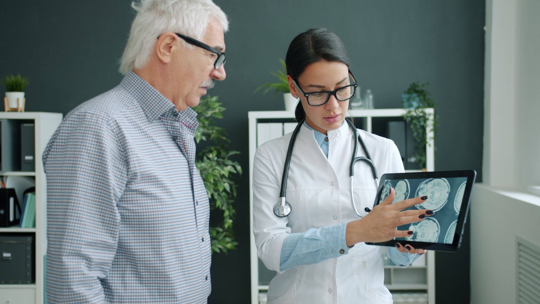 Medical professional reviewing brain scans with an elderly man in a clinic.