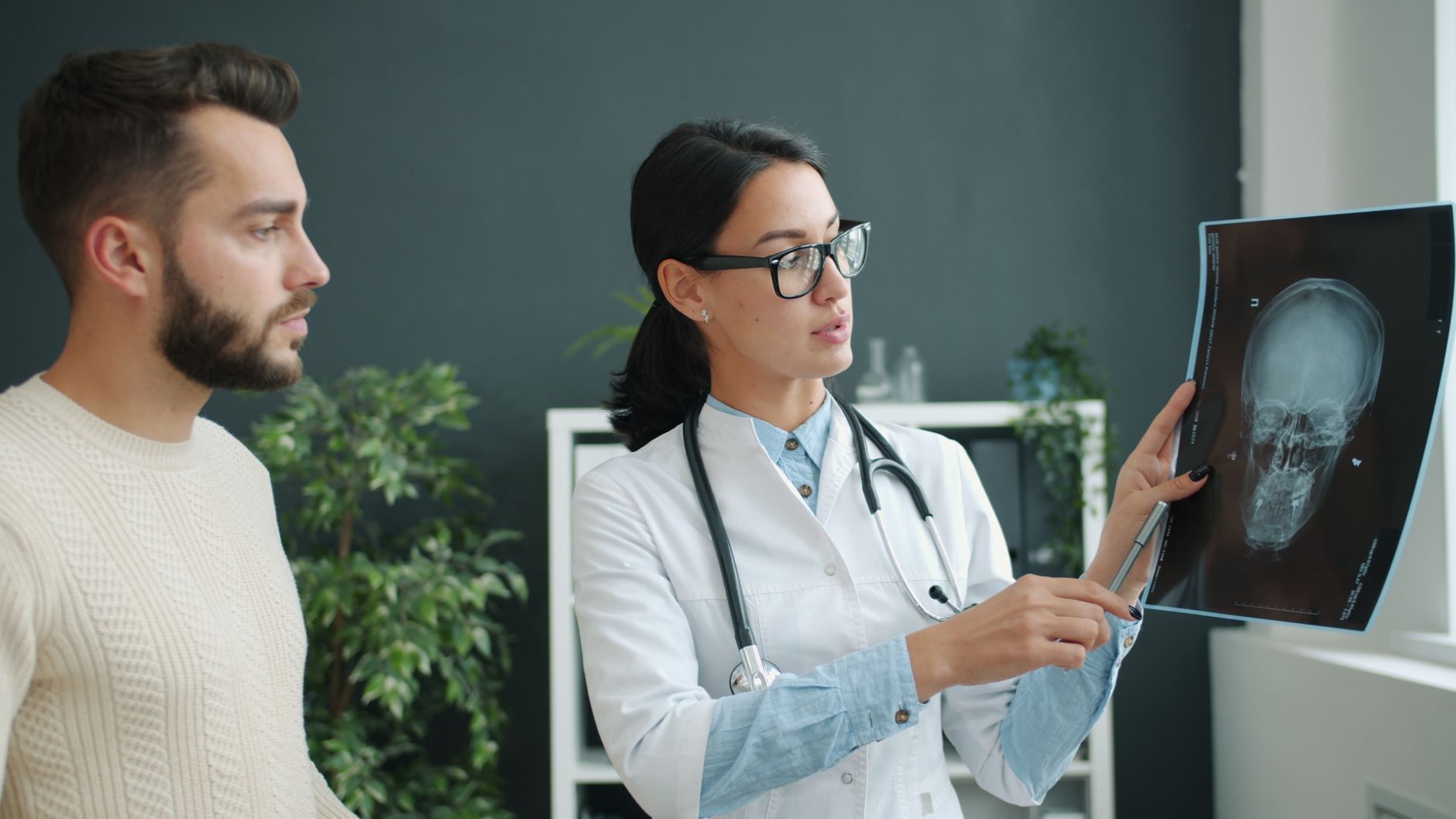 A doctor explains brain X-ray results to a patient in a medical office.