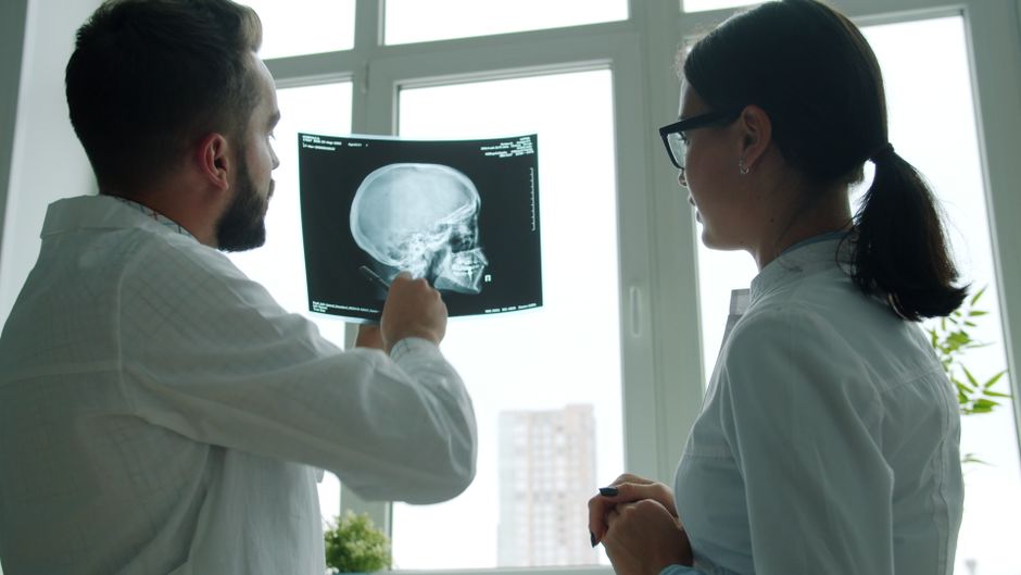 Medical professionals examining an X-ray film in a hospital setting.