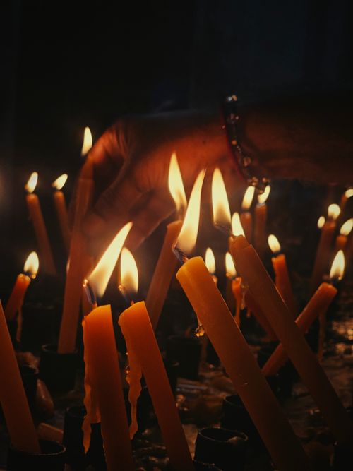 Free A hand placing candles in a warm, dimly lit setting. Stock Photo