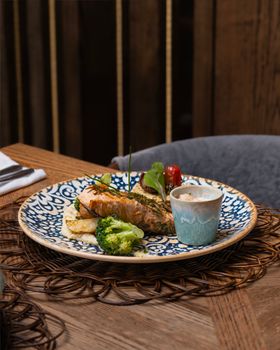 Delicious grilled salmon served with broccoli and gourmet sauce in cozy restaurant setting.