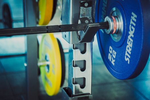 Detailed view of 20 kg weights on a barbell in a gym, emphasizing strength and fitness.