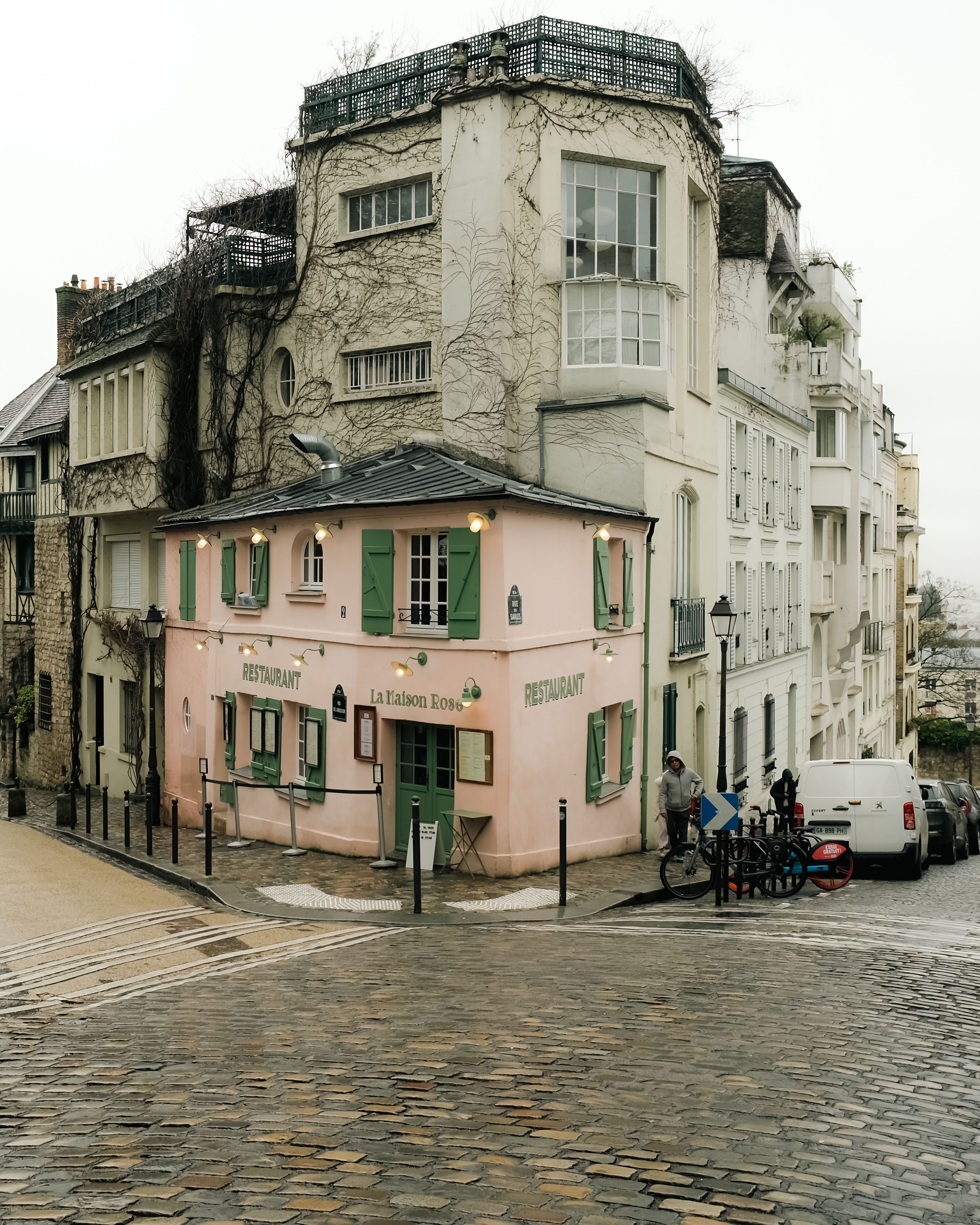 Picturesque view of La Maison Rose in Montmartre, Paris on a cloudy day, showcasing vibrant architecture.