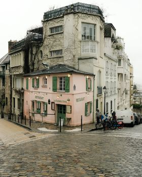 Picturesque view of La Maison Rose in Montmartre, Paris on a cloudy day, showcasing vibrant architecture.