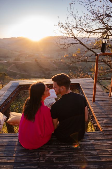 Photo by Wolf Art on Pexels Couple relaxing on a hilltop deck with a stunning sunset view, embracing the serene landscape.
