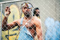 一位穿着充满活力服装的时尚男子站在栅栏旁，城市风格与凉爽氛围十足