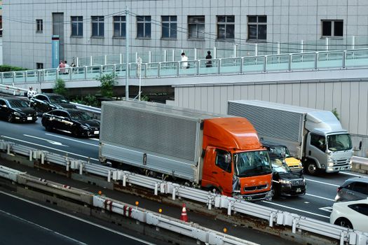 Traffic scene with trucks and cars in Tokyo, Japan, showcasing urban life and transportation.