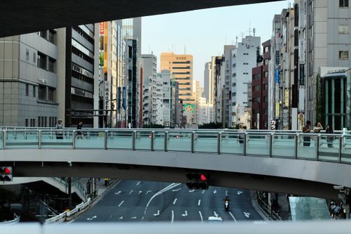 Free A modern view of Tokyo's urban architecture and city life with pedestrians on a bridge. Stock Photo