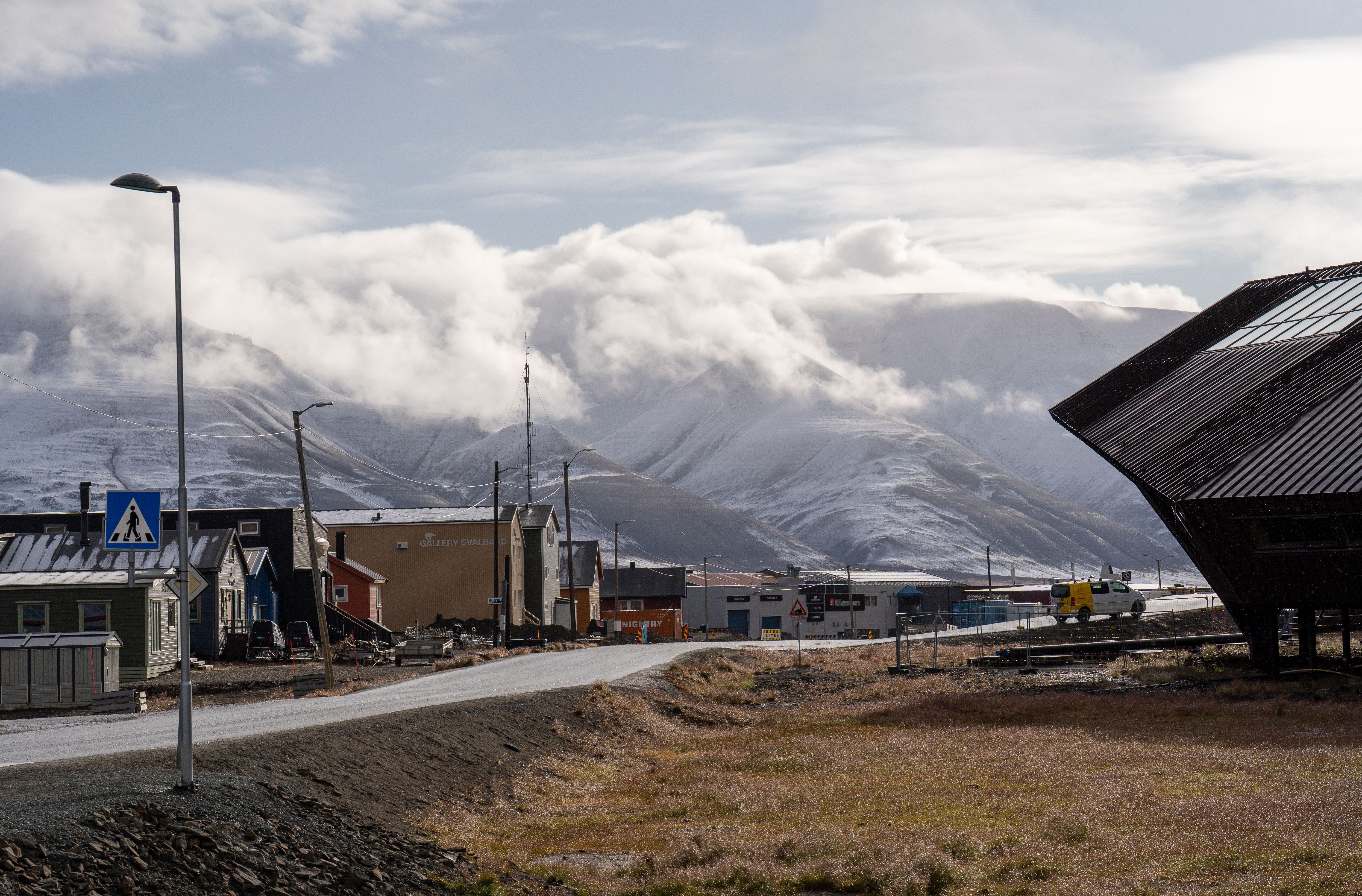 Tranquil arctic town with snow-capped mountains and clouds, capturing serene remote landscape.