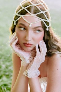 Beautiful portrait of a woman wearing vintage lace gloves and a pearl headpiece outdoors.