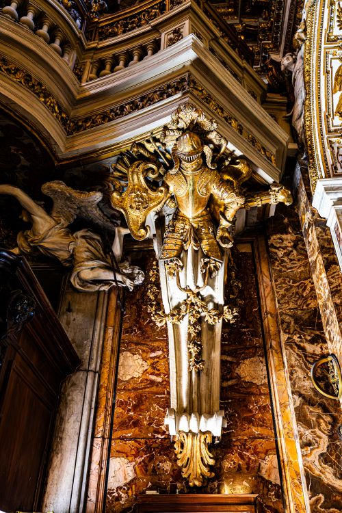 Free Intricate baroque sculpture featuring a golden armored figure inside a Roman church. Stock Photo
