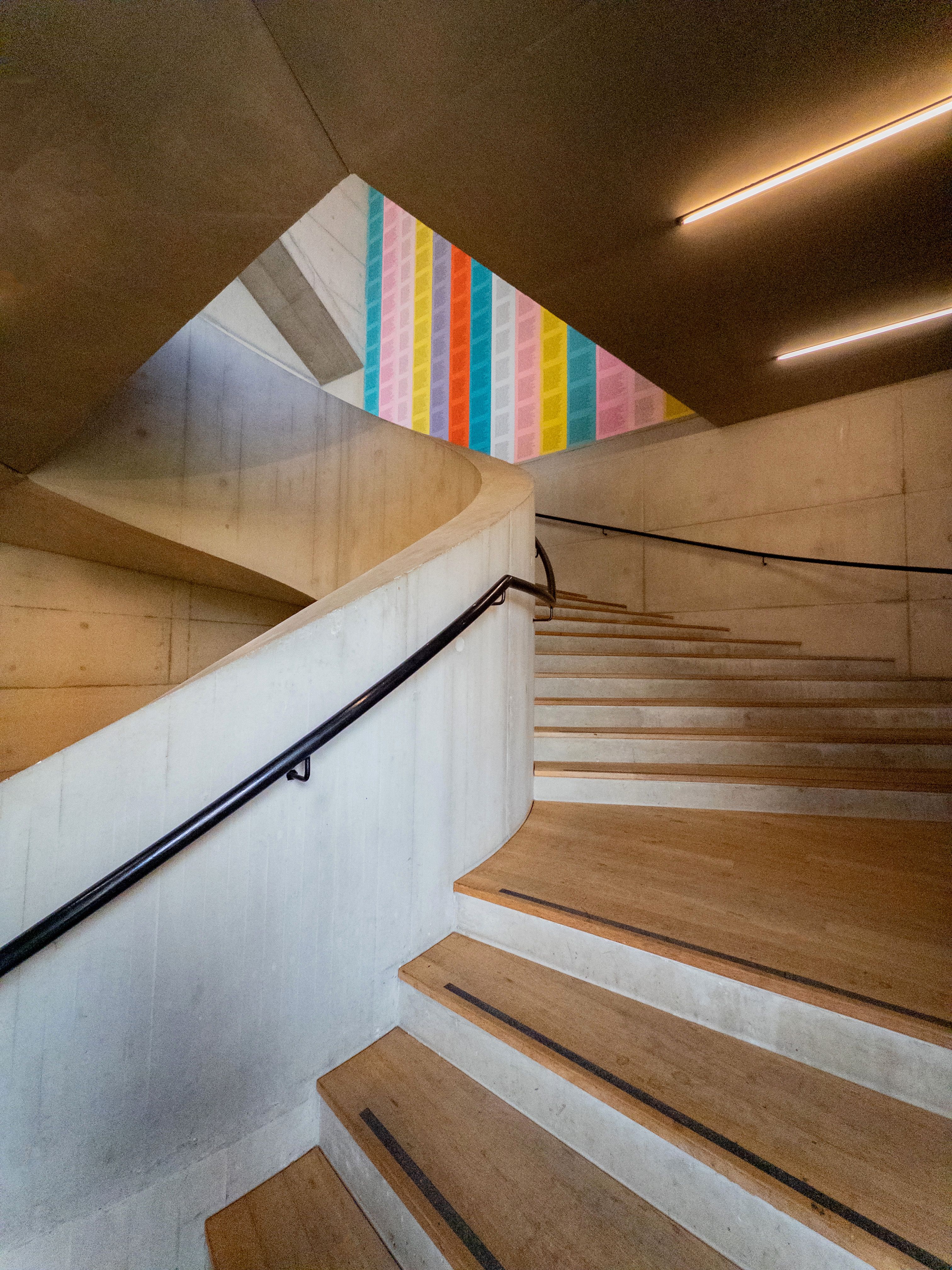 Wooden staircase inside a modern art gallery in London with colorful wall art.