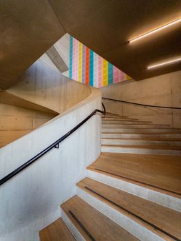 Wooden staircase inside a modern art gallery in London with colorful wall art.