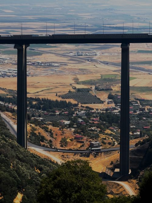 Free A tall bridge spans over a lush countryside with distant fields. Stock Photo