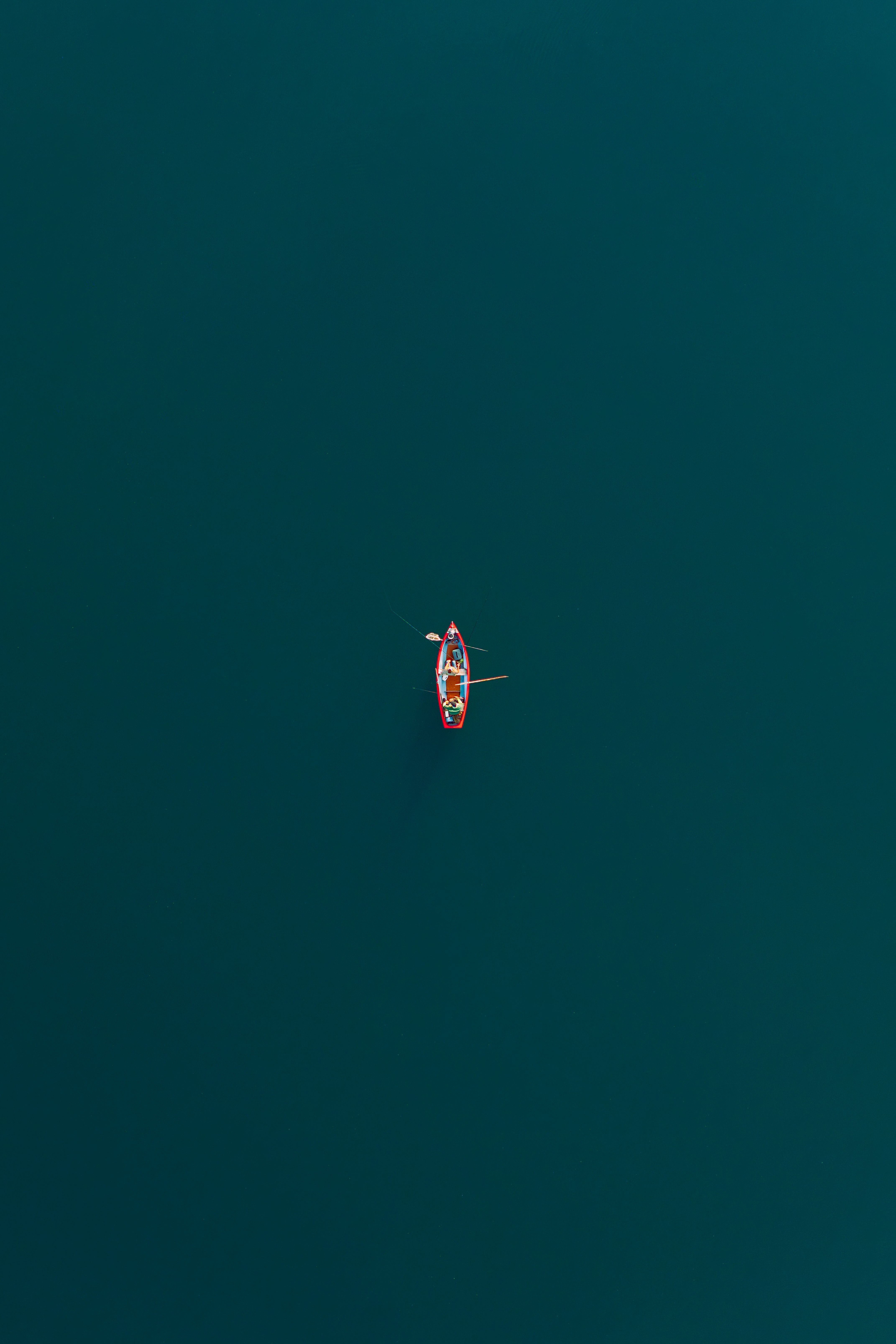 Aerial view of a lone rowboat on the tranquil waters of Kochel Lake, Bavaria, showcasing minimalist beauty.
