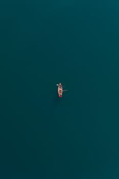 Aerial view of a lone rowboat on the tranquil waters of Kochel Lake, Bavaria, showcasing minimalist beauty.