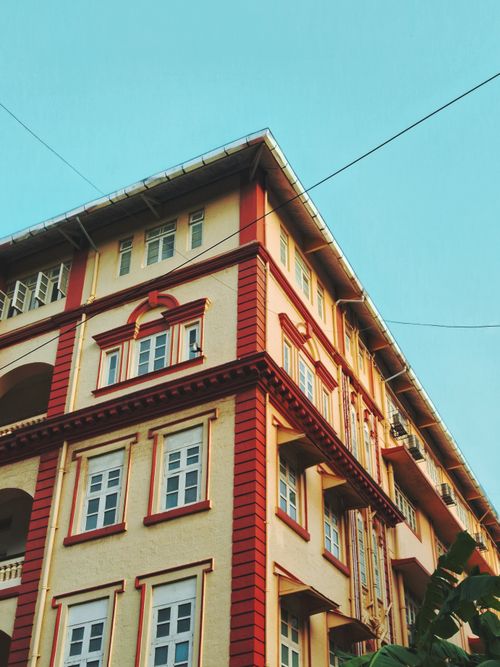 Free A colorful, classic building with bright red accents against a clear blue sky. Stock Photo