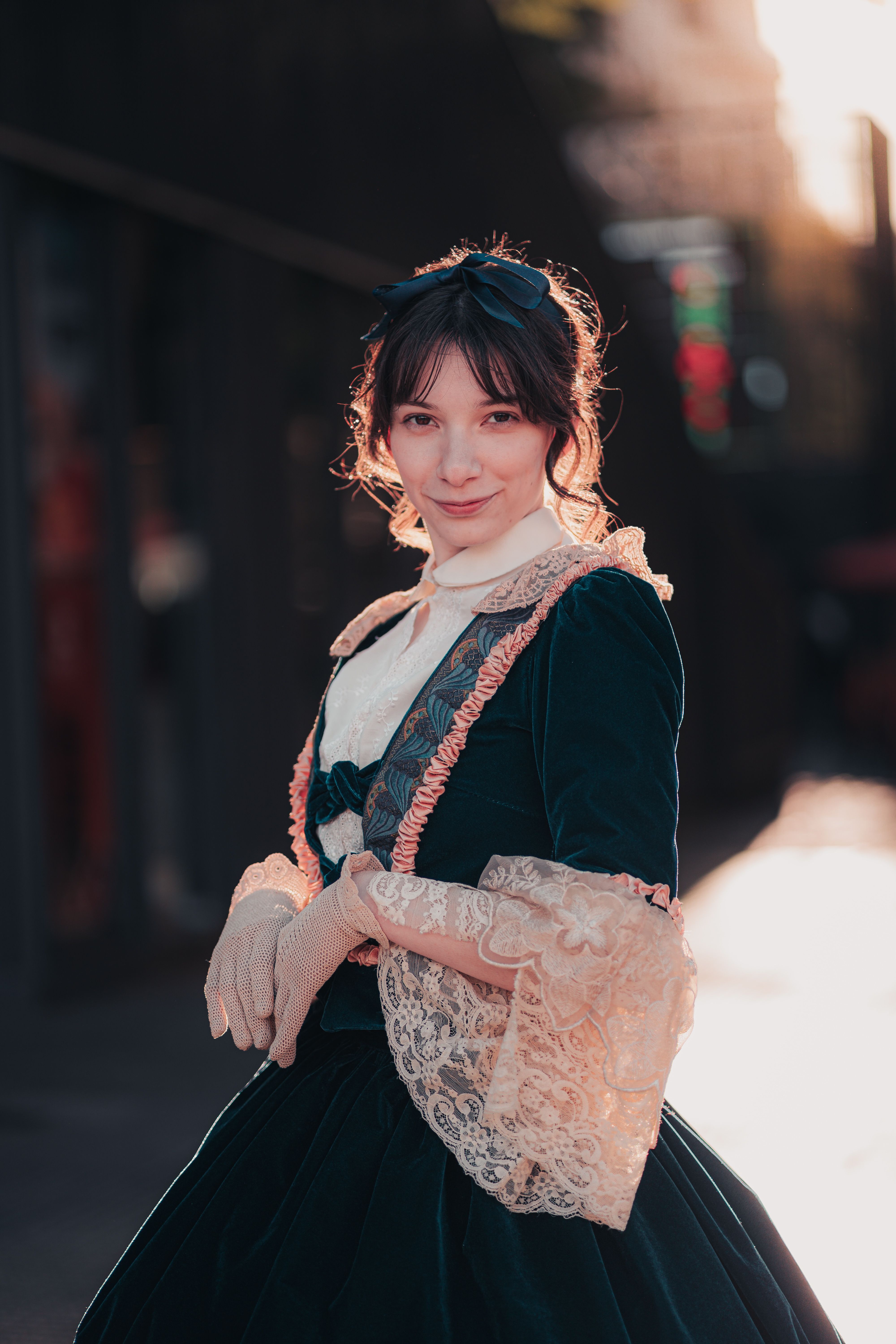 Charming portrait of woman in vintage dress with lace and gloves, captured outdoors in sunlight.