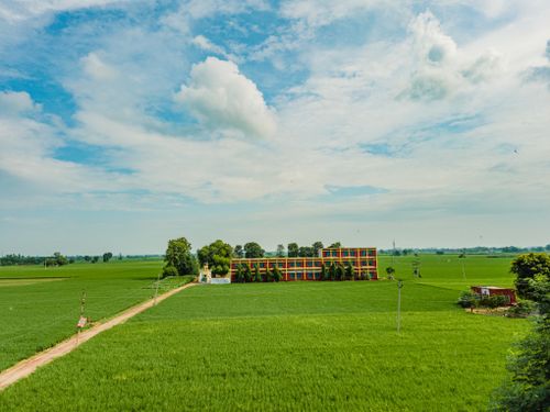 Free Vibrant green fields and colorful building create a serene rural landscape under a clear blue sky. Stock Photo