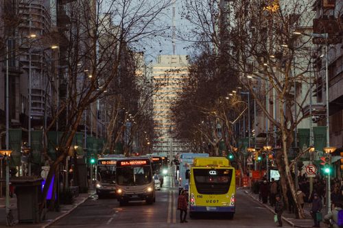 Free A bustling Montevideo street with buses and pedestrians at dusk, showcasing city life in Uruguay. Stock Photo