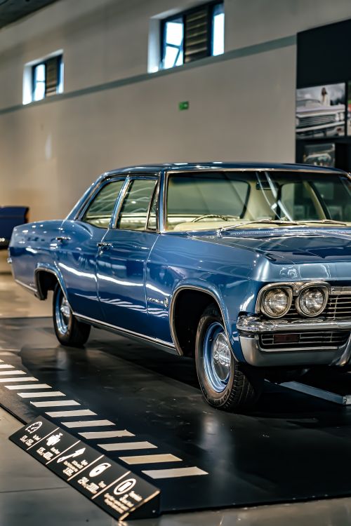 Free Classic blue American car exhibited in a contemporary showroom setting. Stock Photo