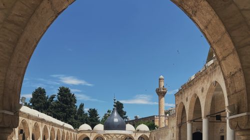 Free A medieval mosque courtyard featuring arches and a stunning blue sky, showcasing Islamic architecture. Stock Photo