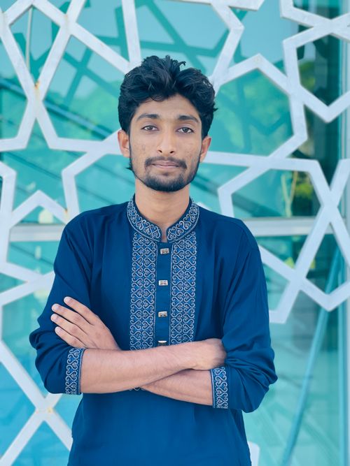Free Portrait of a young man in elegant traditional attire against a geometric patterned backdrop. Stock Photo