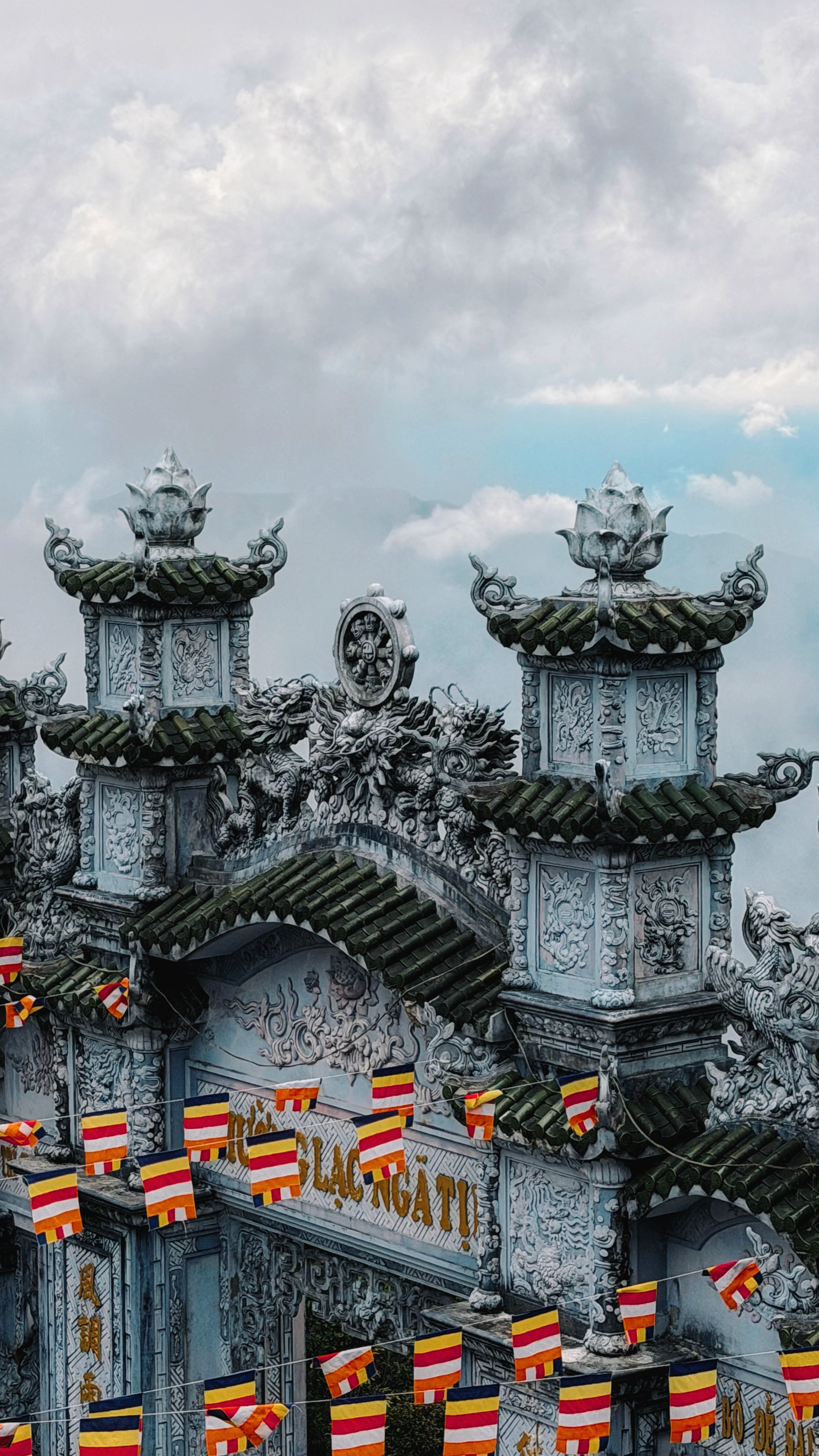 A detailed view of a Buddhist temple gate adorned with flags in Đà Nẵng, Vietnam.